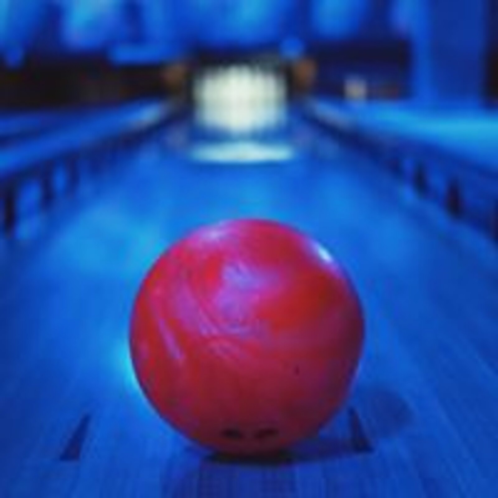 Burgunder-rød bowlingkule på banen i blått disco-lys